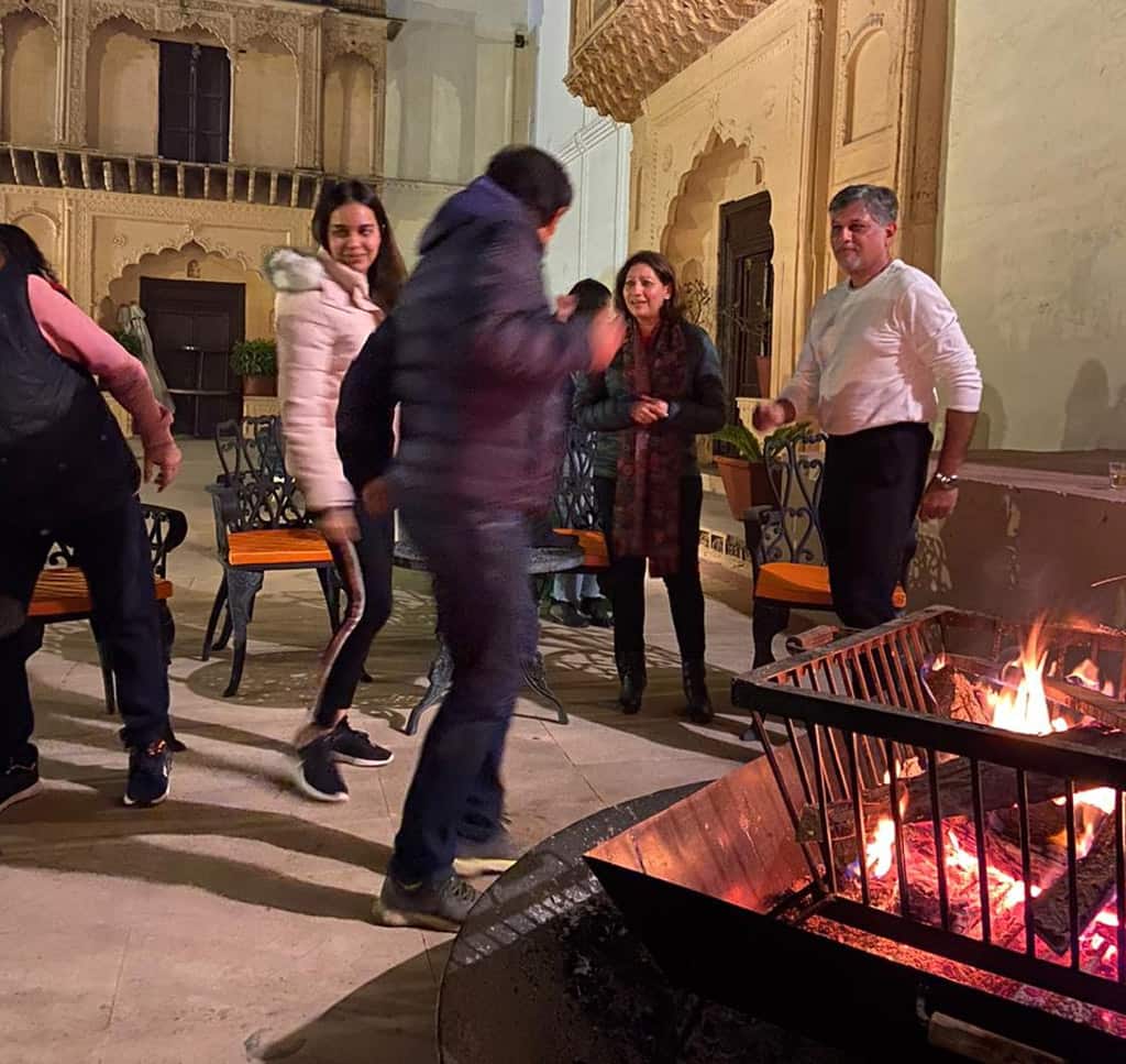Guests enjoying a cozy bonfire evening at a family resort near Delhi.